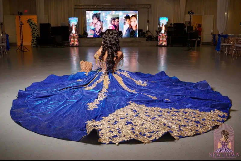 Quinceañera in a blue and gold gown facing the LED photo wall on the dance floor at a DJ Oso event